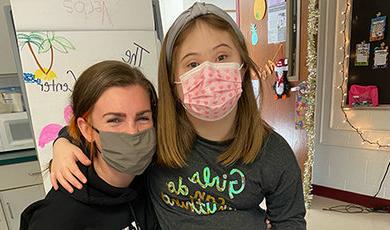 Nikki Maloney poses for a photo in a classroom with a student.